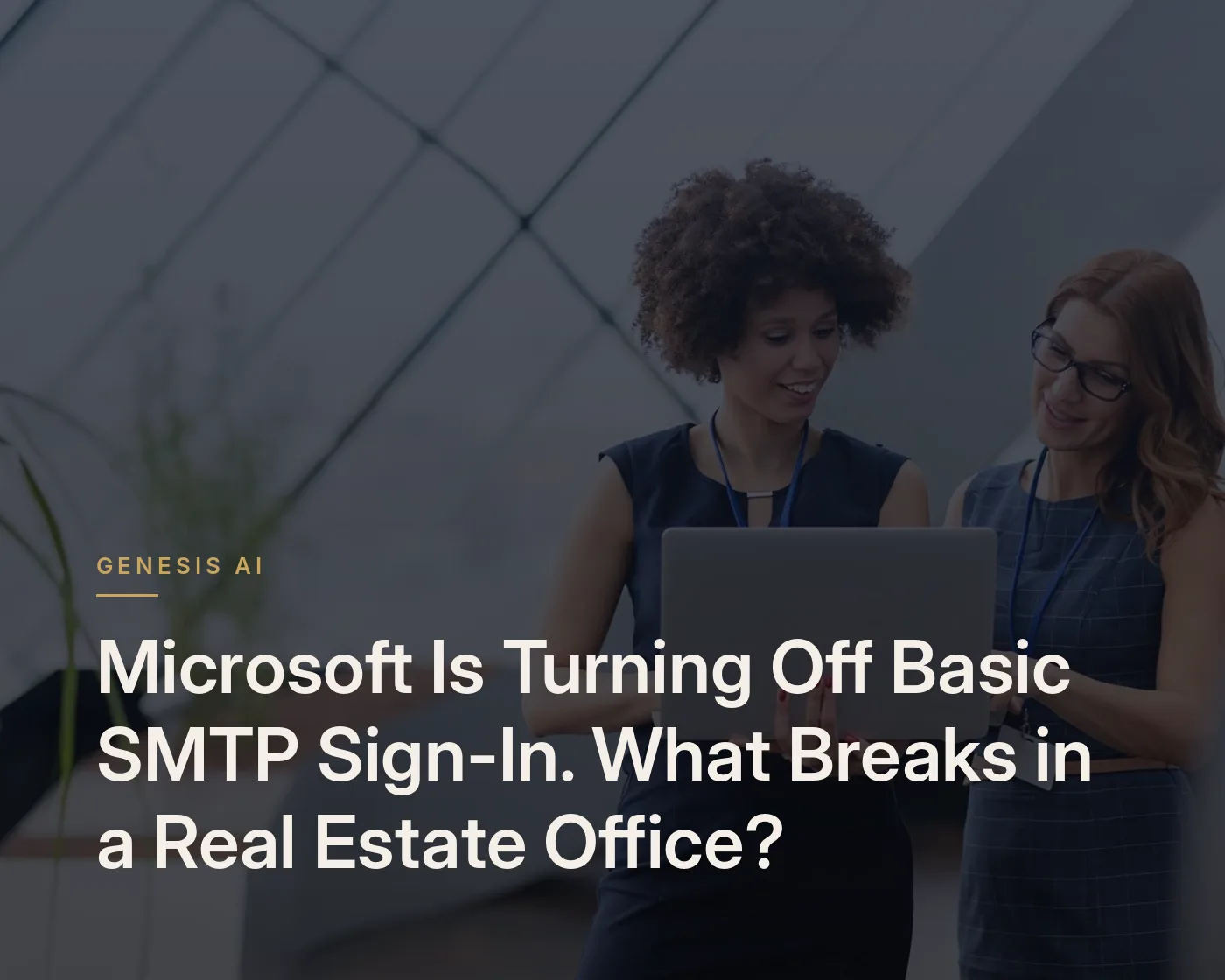 Two colleagues standing in a bright, glass-roofed office, one holding an open laptop while they review it together