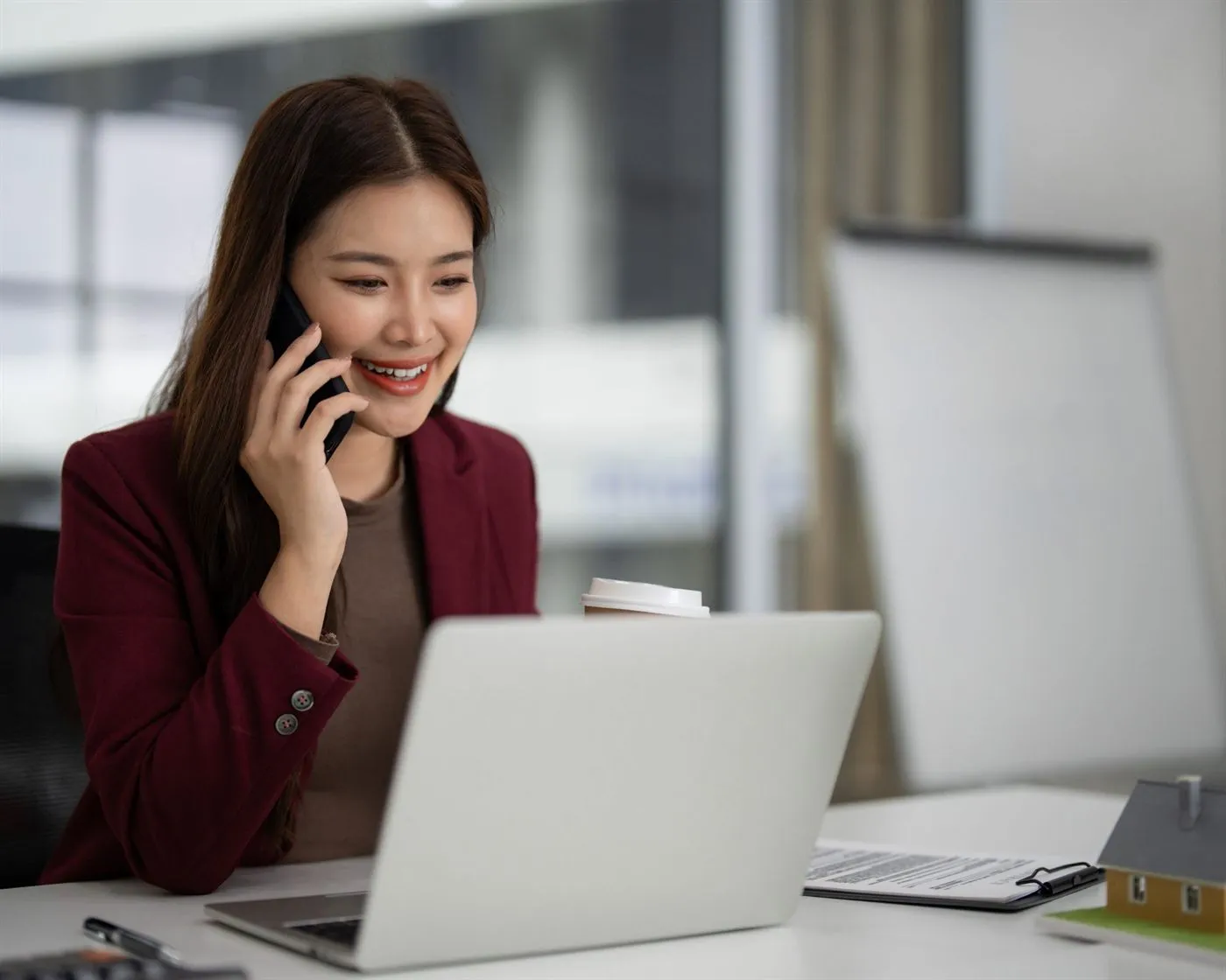 A real estate agent taking a call at her desk beside a laptop