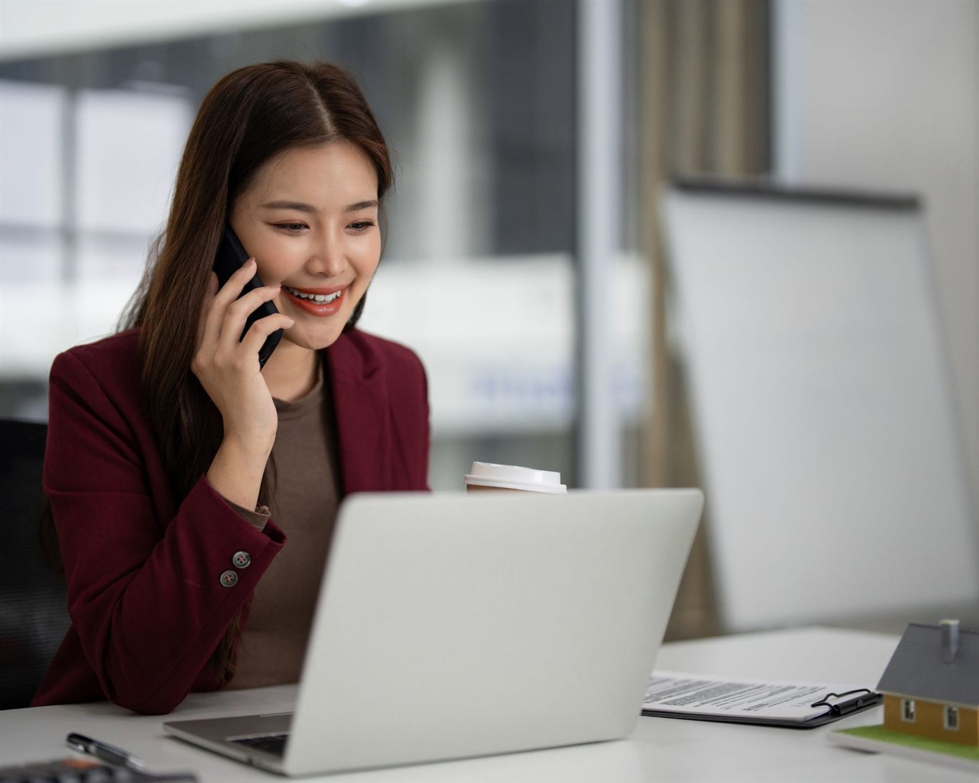 A real estate agent taking a call at her desk beside a laptop