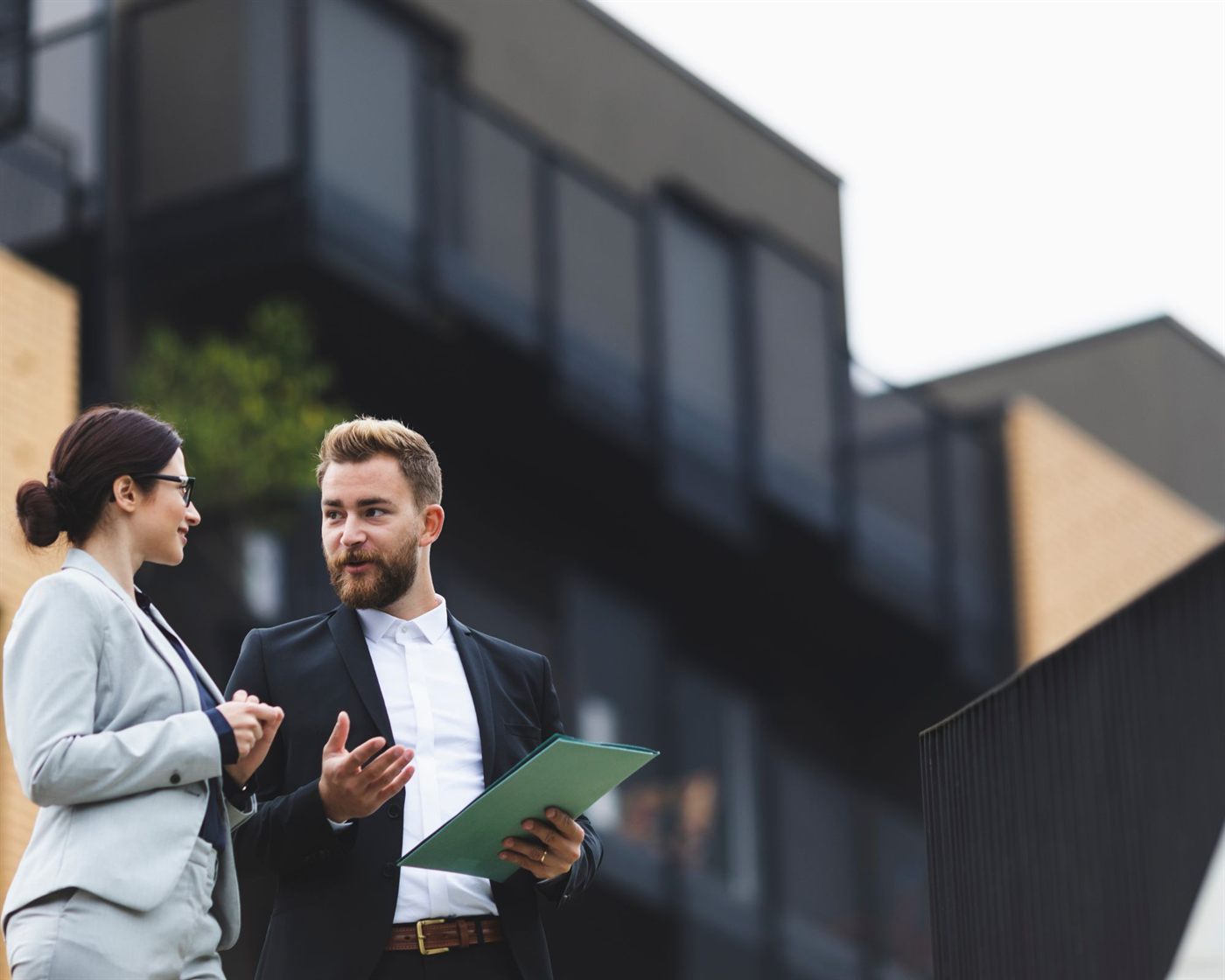 Two real estate professionals talking outside an office building