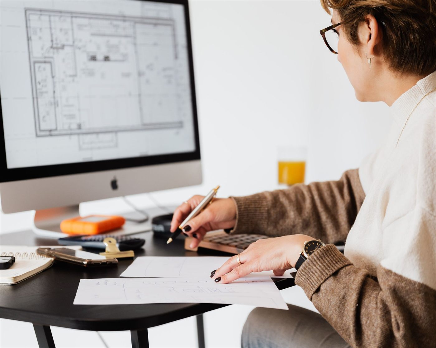 A real estate professional working at a desk with a floor plan on screen