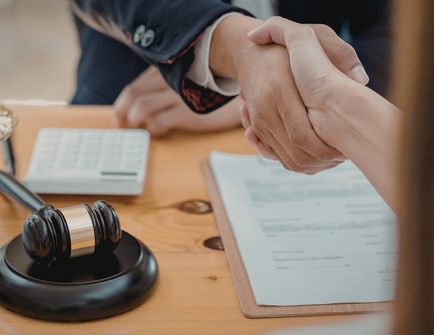 Attorney and client shaking hands over legal documents